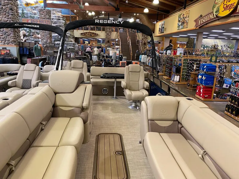 Slide: The Image of 2025 Regency 250 DL3 pontoon boat displayed in a store with beige seating and elegant interior. - 2