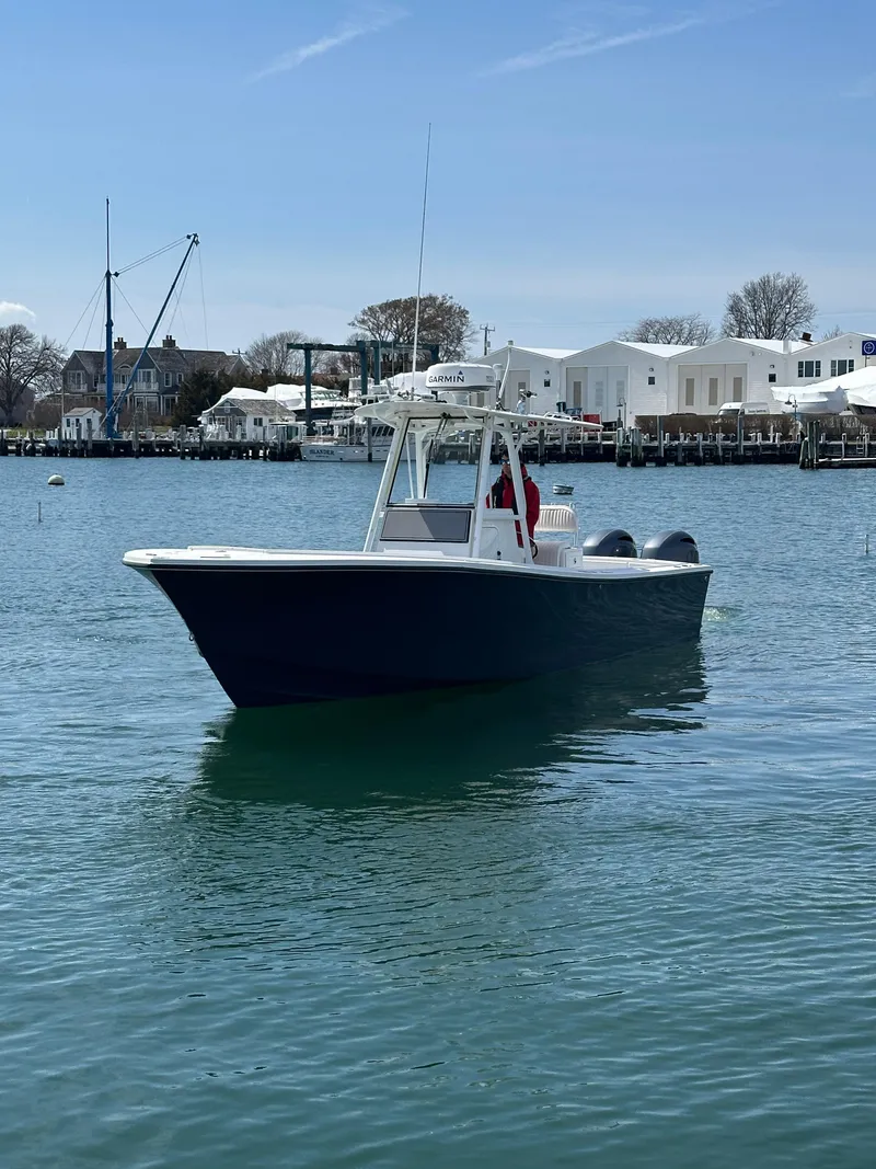 Slide: The Image of 2003 Regulator 26 Center Console boat on calm water near a marina. - 1