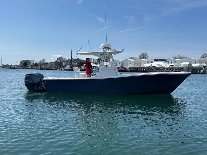 Slide: The Image of 2003 Regulator 26 Center Console boat on calm water, clear sky background. - 10