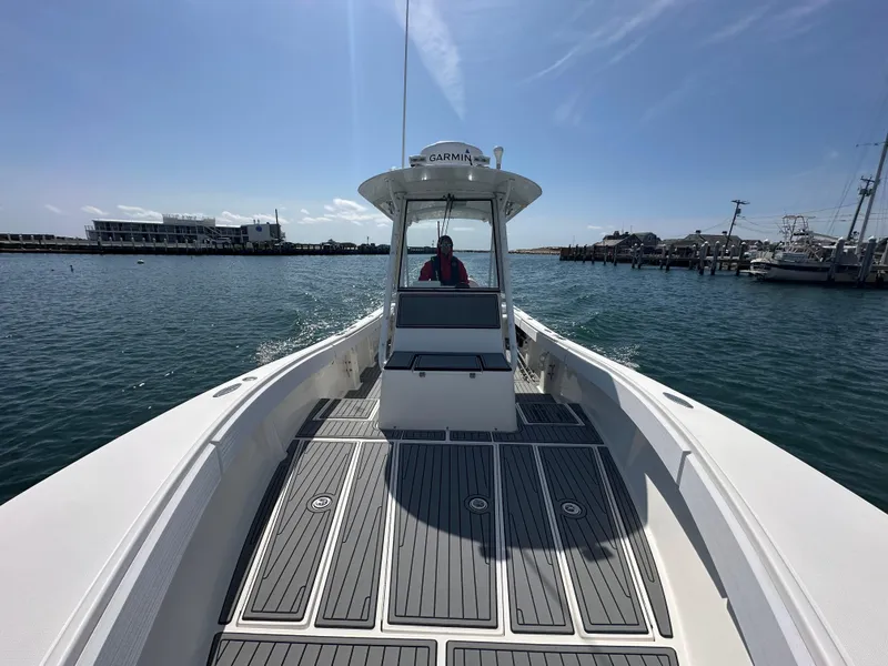 Slide: The Image of 2003 Regulator 26 Center Console boat cruising in a sunny harbor. - 14