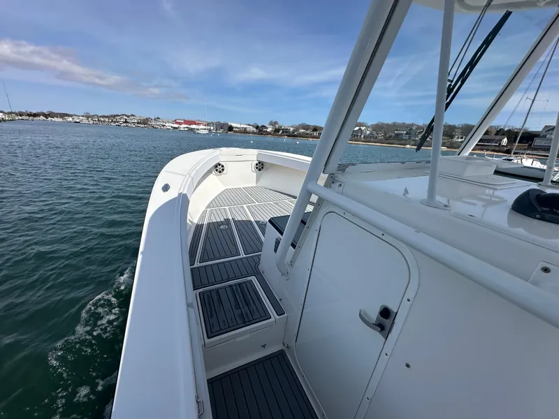 Slide: The Image of 2003 Regulator 26 Center Console boat on calm water, showcasing deck and coastal view. - 16