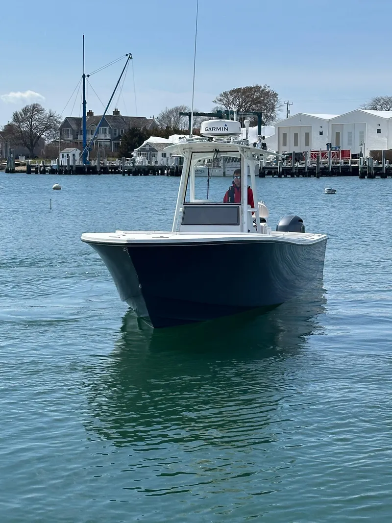 Slide: The Image of 2003 Regulator 26 Center Console boat on calm water near a marina. - 2