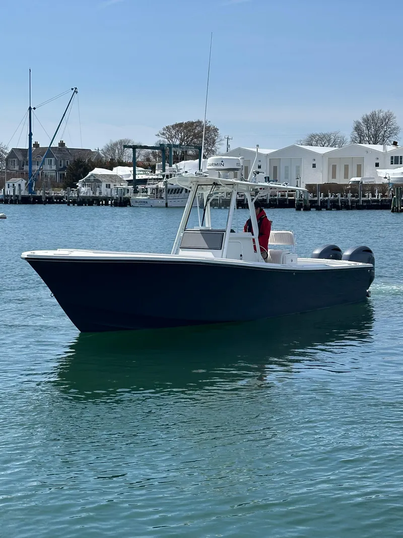 Slide: The Image of 2003 Regulator 26 Center Console boat on calm water near a marina. - 3