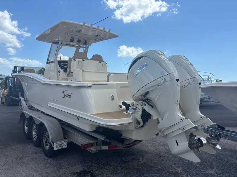 Slide: The Image of 2025 Scout 277 LXF boat with dual outboard engines on a trailer, under a clear blue sky. - 1