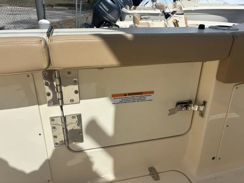 Slide: The Image of 2025 Scout 277 LXF boat interior with beige seating and safety warning label. - 19