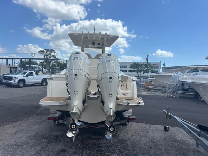 Slide: The Image of 2025 Scout 277 LXF boat with dual outboard engines, parked outdoors under a blue sky. - 2