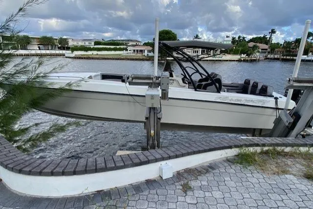 Slide: The Image of 1996 Powerplay Powerboats 33 Sportfish on lift by waterfront, cloudy sky background. - 5