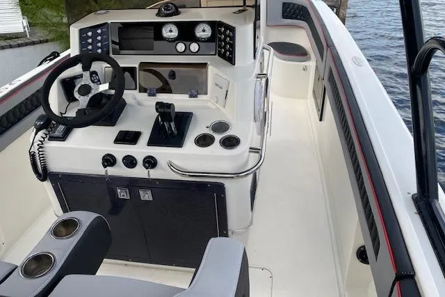 Slide: The Image of 1996 Powerplay Powerboats 33 Sportfish cockpit with steering wheel, controls, and gauges by the water. - 8