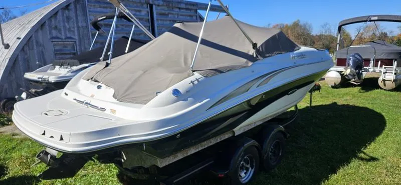 Slide: The Image of 2003 Sea Ray 220 Sundeck boat covered, parked on trailer in grassy area. - 5