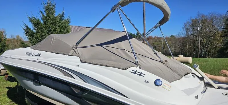 Slide: The Image of 2003 Sea Ray 220 Sundeck boat with cover, parked on grass under clear blue sky. - 7