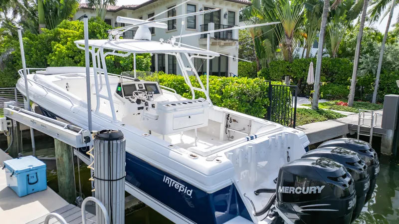 Slide: The Image of 2008 Intrepid 370 Cuddy boat docked, featuring dual Mercury engines, surrounded by lush greenery. - 42