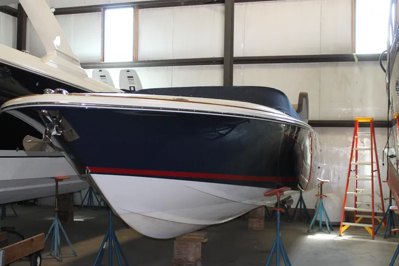 Slide: The Image of 2007 Chris-Craft Launch 28 boat in storage, blue hull with red stripe, elevated on stands. - 0