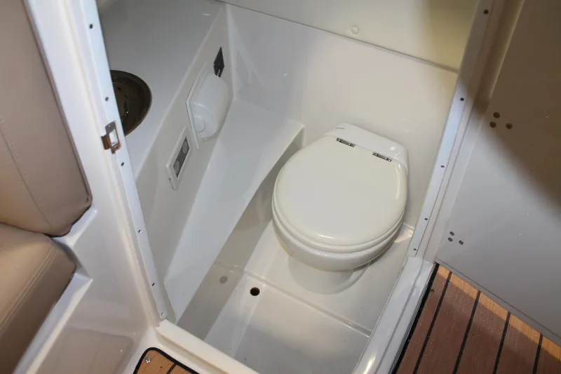 Slide: The Image of 2007 Chris-Craft Launch 28 boat interior with compact marine toilet and wooden flooring. - 10