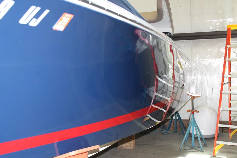 Slide: The Image of 2007 Chris-Craft Launch 28 boat in storage, blue hull with red stripe, ladder nearby. - 2