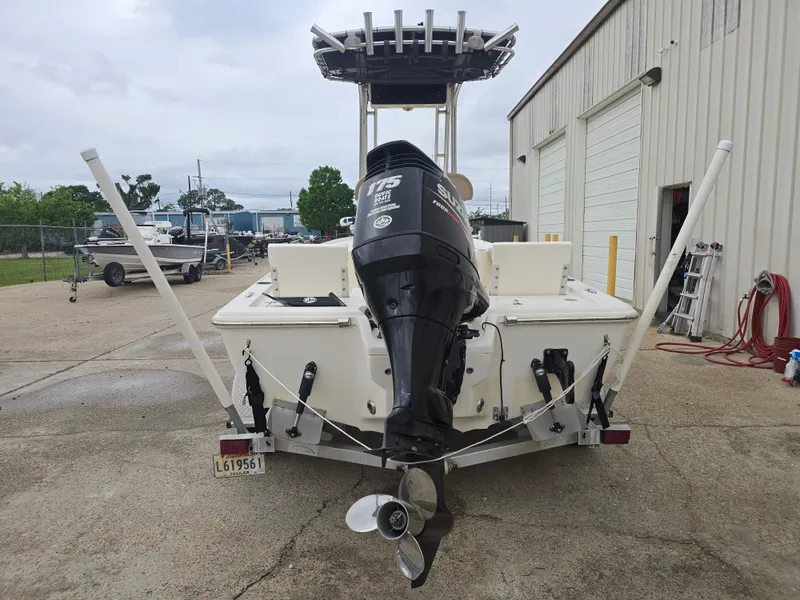 Slide: The Image of 2014 Key West 210 Bay Reef boat with outboard motor, parked near a warehouse. - 4