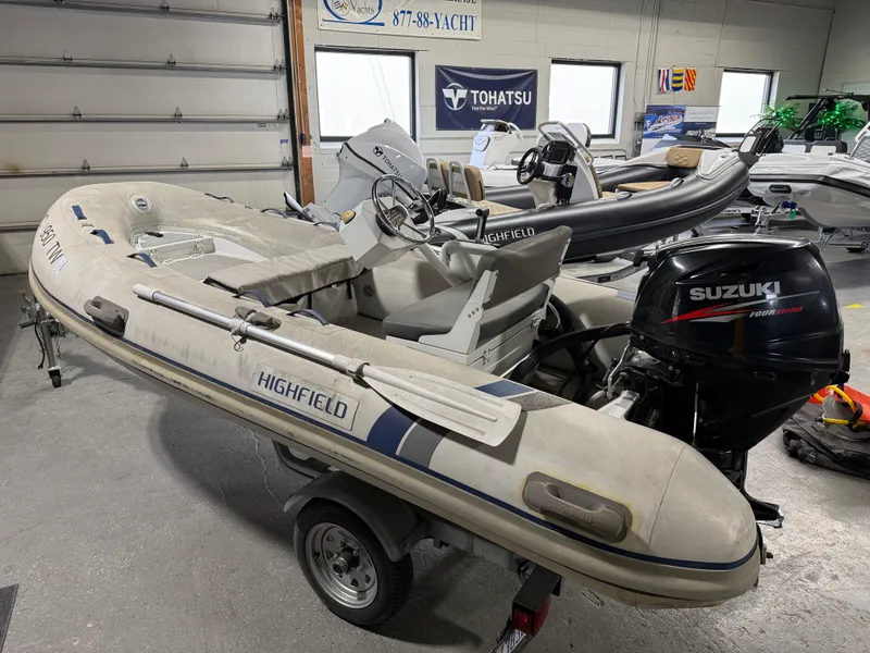 Slide: The Image of 2016 Highfield Classic 360 FCT inflatable boat with Suzuki outboard motor in a garage. - 1