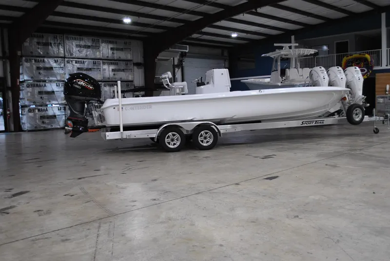 Slide: The Image of 2025 Contender 25 Bay boat on trailer in spacious indoor facility. - 1