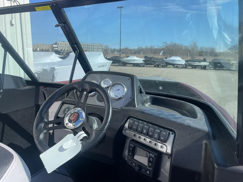 Slide: The Image of 2024 Alumacraft Competitor 205 Sport dashboard with steering wheel and controls in outdoor setting. - 13