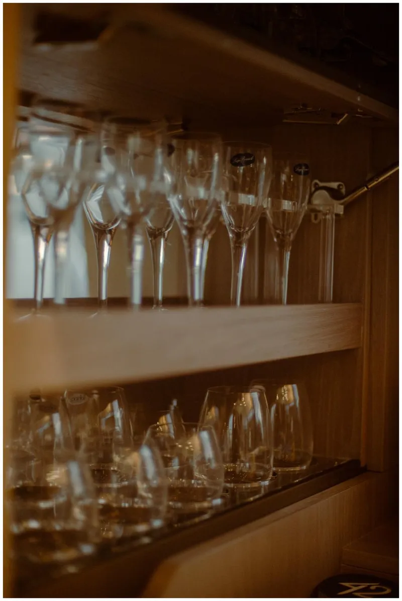Slide: The Image of Wine glasses neatly arranged in a wooden cabinet on a 2022 Azimut Fly yacht. - 43