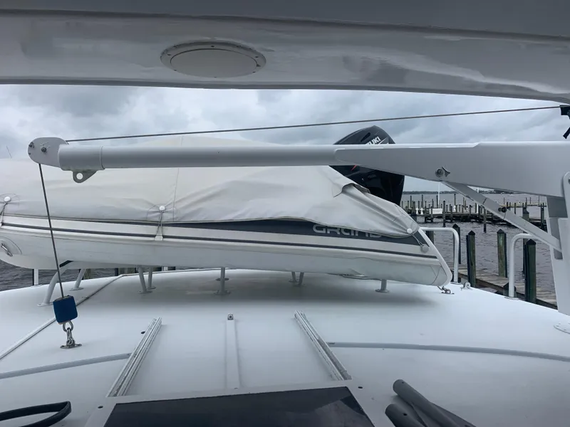 Slide: The Image of 1998 Hatteras 52 Cockpit Motor Yacht with covered dinghy on deck, docked under cloudy skies. - 14