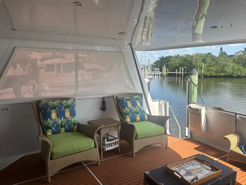 Slide: The Image of 1998 Hatteras 52 Cockpit Motor Yacht interior with tropical-themed seating by the water. - 16