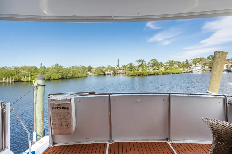 Slide: The Image of 1998 Hatteras 52 Cockpit Motor Yacht with scenic water view and wooden deck. - 18
