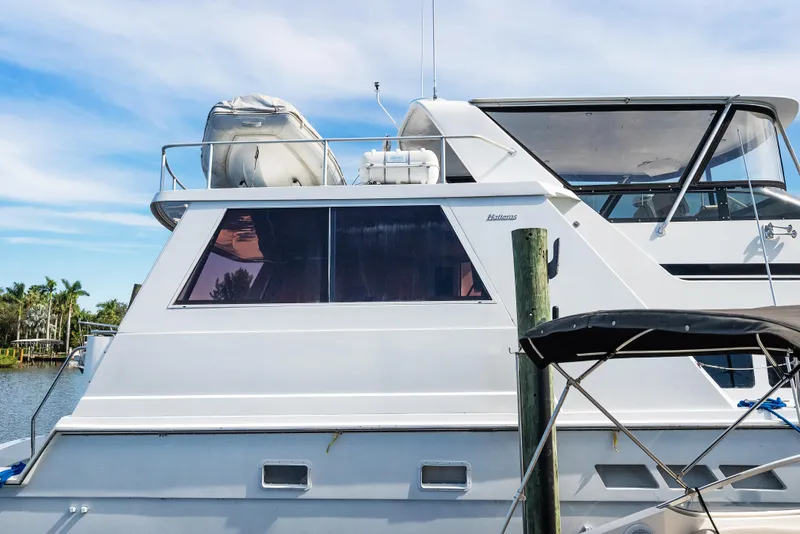 Slide: The Image of 1998 Hatteras 52 Cockpit Motor Yacht docked, featuring sleek design and spacious upper deck. - 2