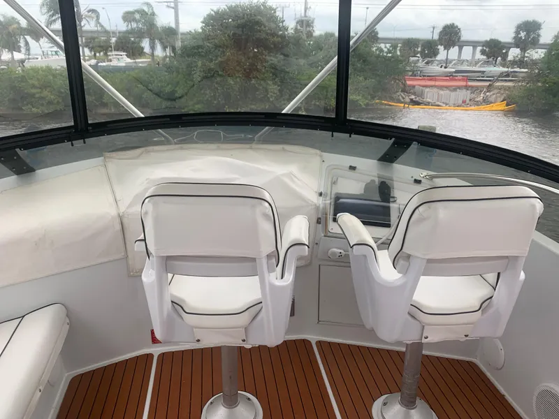 Slide: The Image of 1998 Hatteras 52 Cockpit Motor Yacht helm with white seats and wooden flooring. - 4