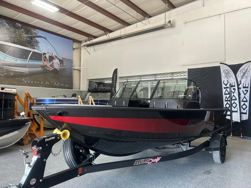 Slide: The Image of 2024 Alumacraft Competitor FSX 185 boat in showroom, black and red design, on trailer. - 3