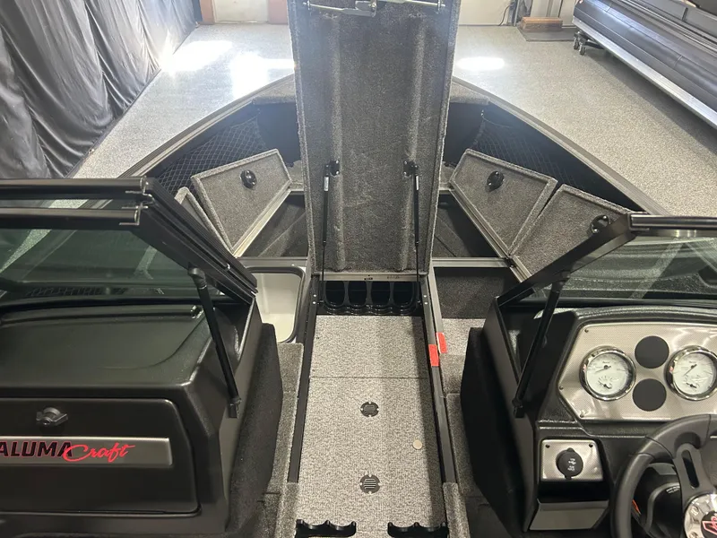 Slide: The Image of 2024 Alumacraft Competitor FSX 175 interior with open storage compartments and dashboard view. - 9