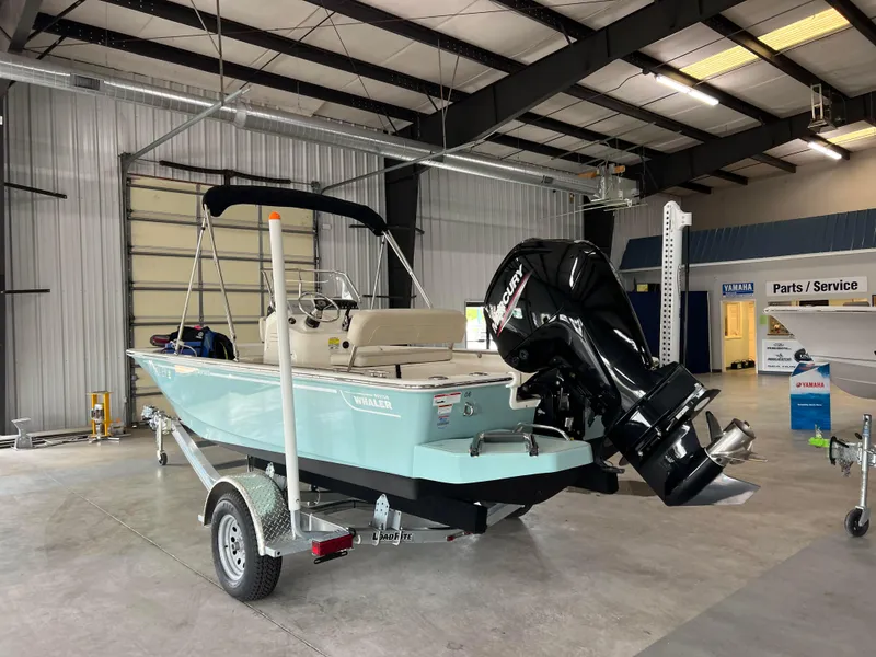 Slide: The Image of 2022 Boston Whaler 170 Montauk boat in a showroom, featuring a powerful outboard motor. - 5