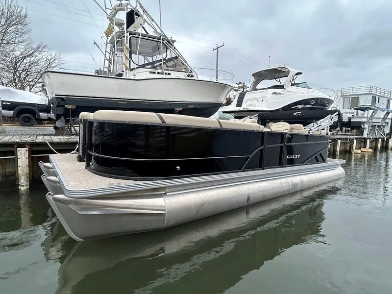 Slide: The Image of 2024 Crest Classic DLX 240 SLC pontoon boat docked in a marina. - 0