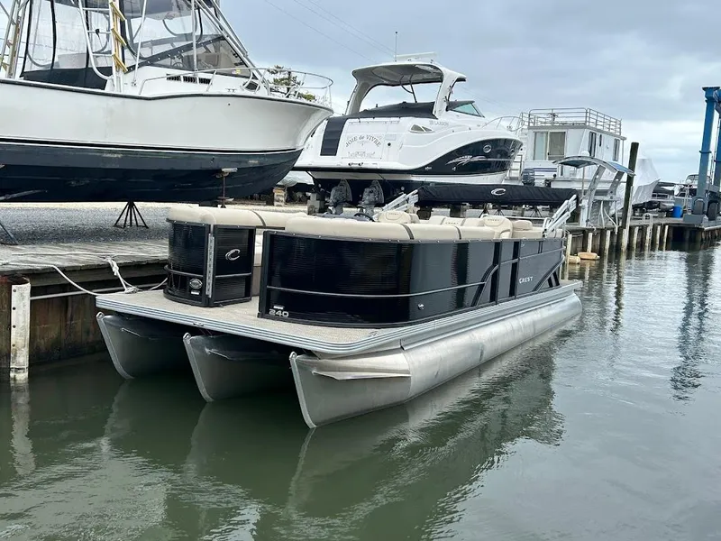 Slide: The Image of 2024 Crest Classic DLX 240 SLC pontoon boat docked in marina. - 2