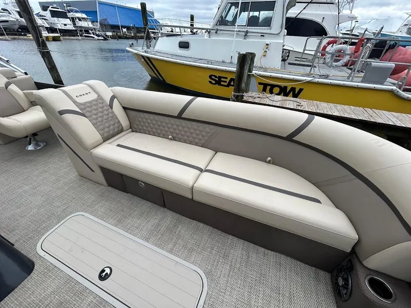 Slide: The Image of 2024 Crest Classic DLX 240 SLC boat interior with beige seating at marina. - 6