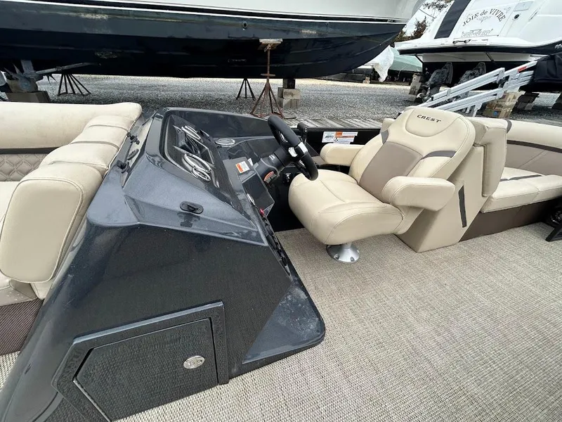 Slide: The Image of 2024 Crest Classic DLX 240 SLC boat interior with beige seating and steering console. - 8