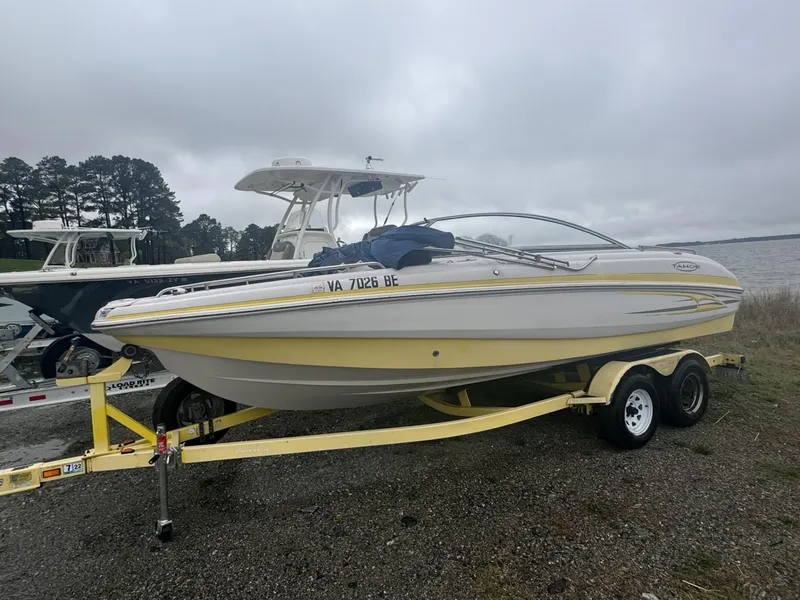 Slide: The Image of 2006 Tahoe 215 boat on trailer near water, overcast sky. - 2