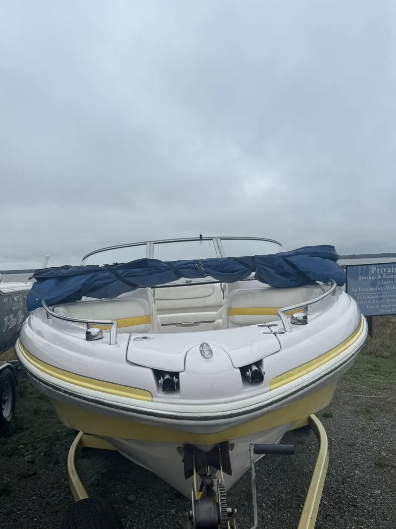 Slide: The Image of 2006 Tahoe 215 boat with blue cover on a trailer, overcast sky. - 3