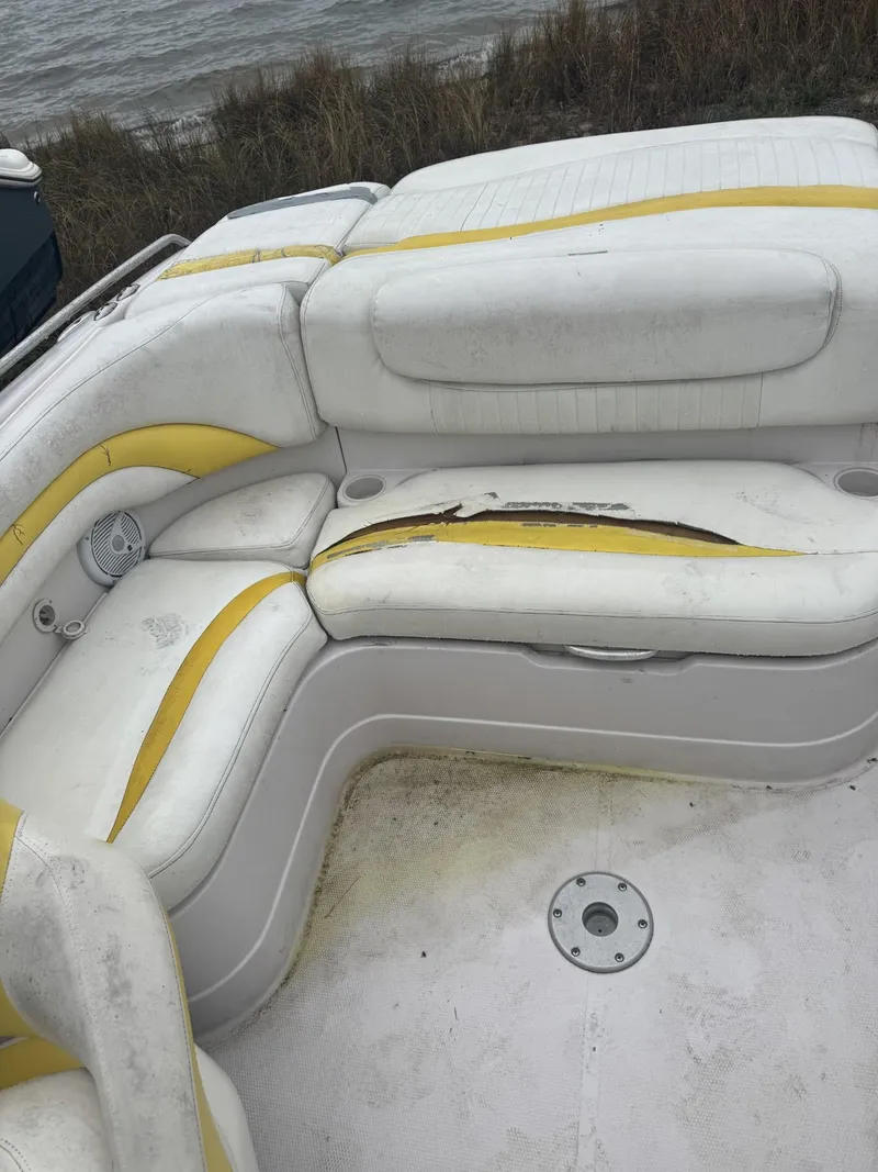 Slide: The Image of 2006 Tahoe 215 boat interior with worn white and yellow seating near water. - 5