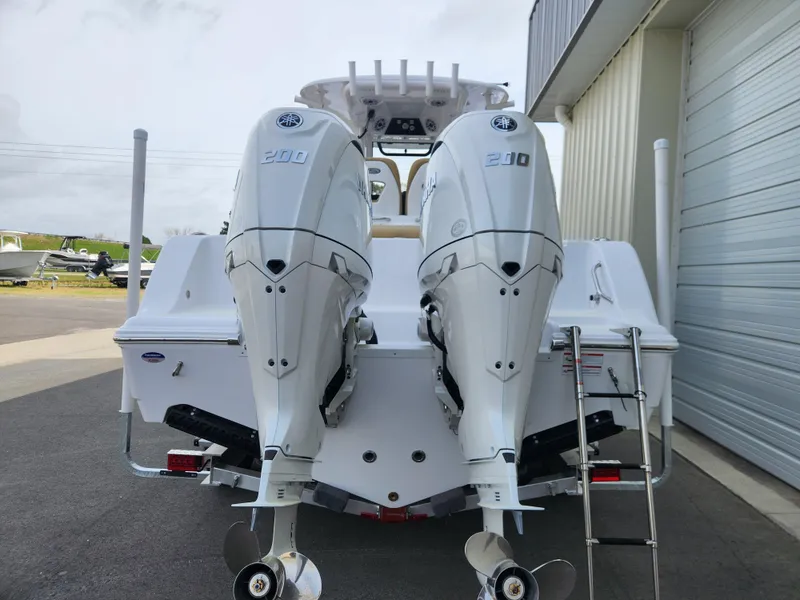 Slide: The Image of 2025 Sportsman Open 262 Center Console with twin outboard engines, docked near a building. - 6