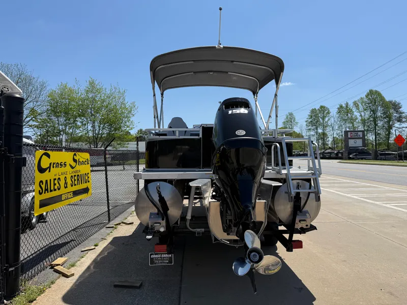 Slide: The Image of 2022 Avalon Venture Fish pontoon boat with outboard motor, parked near sales and service sign. - 19