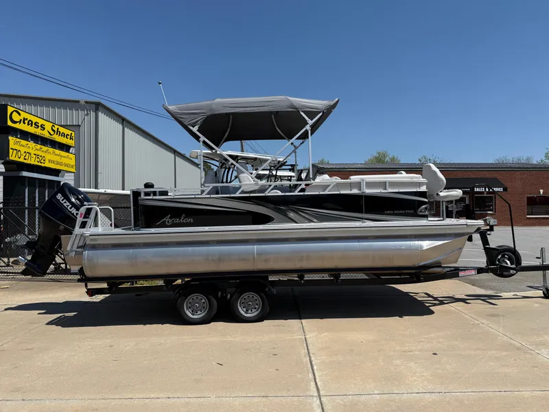 Slide: The Image of 2022 Avalon Venture Fish boat on trailer, parked outside a building under clear blue sky. - 23