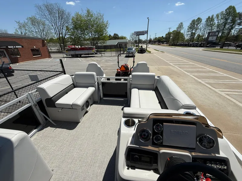 Slide: The Image of 2022 Avalon Venture Fish pontoon boat interior with seating and control panel, parked near a road. - 44