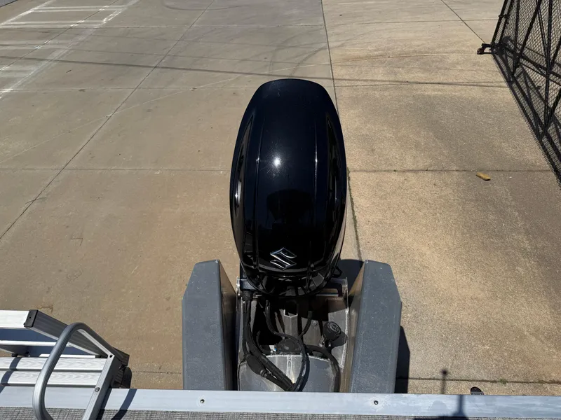 Slide: The Image of 2022 Avalon Venture Fish boat with a black outboard motor, parked on concrete. - 49