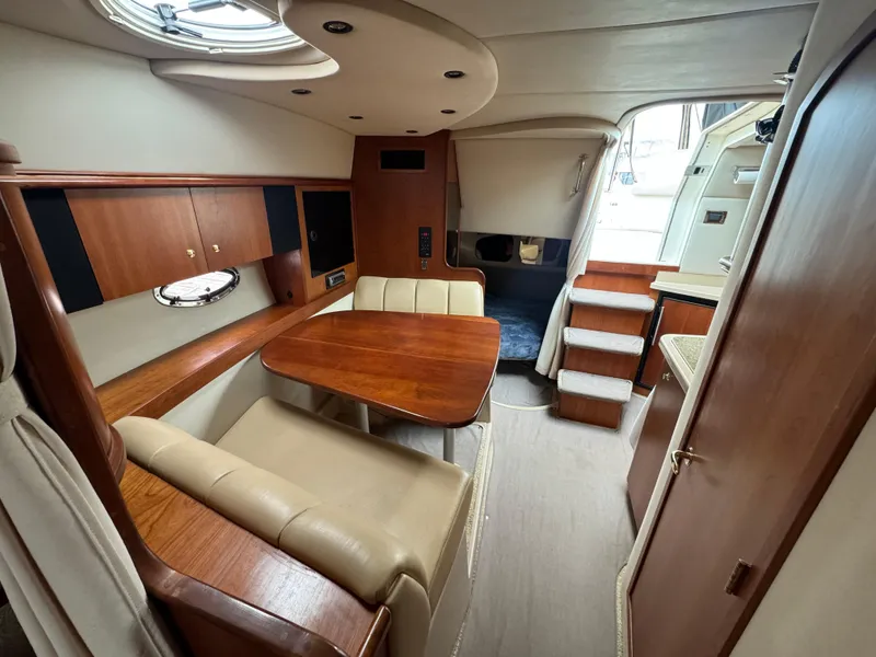 Slide: The Image of 2001 Cruisers Yachts 3470 Express interior with dining area, wood finishes, and stairs to deck. - 11