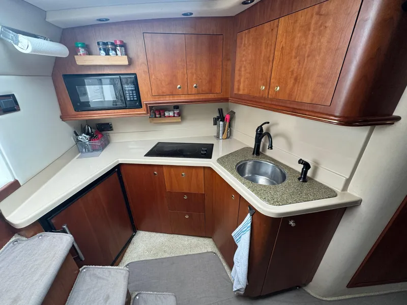 Slide: The Image of 2001 Cruisers Yachts 3470 Express kitchen with wood cabinets, sink, and microwave. - 13