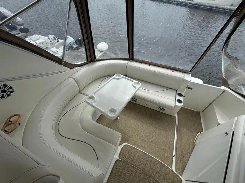 Slide: The Image of 2001 Cruisers Yachts 3470 Express interior with white seating and table, overlooking water. - 17