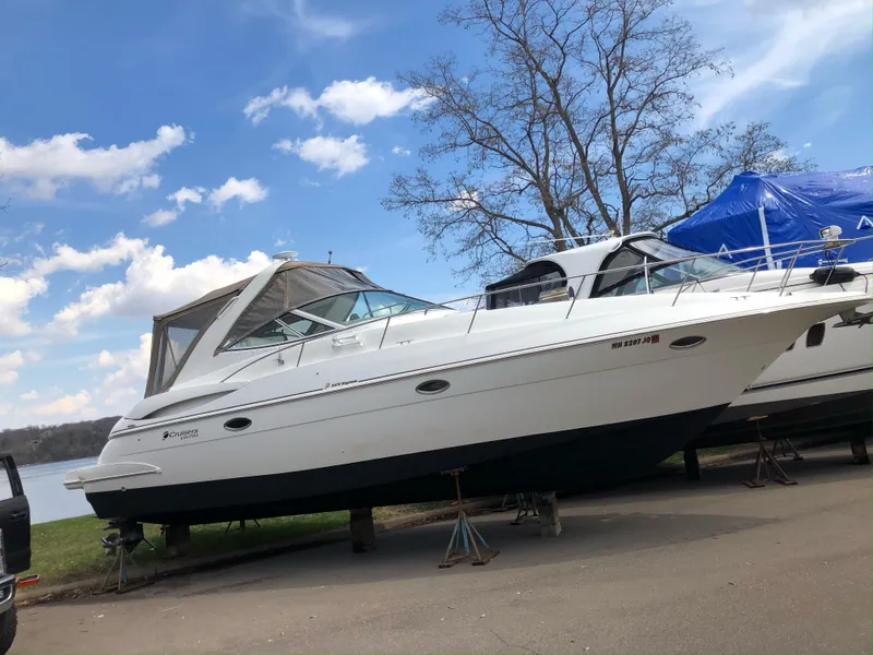 Slide: The Image of 2001 Cruisers Yachts 3470 Express boat on stands, under a clear blue sky. - 3