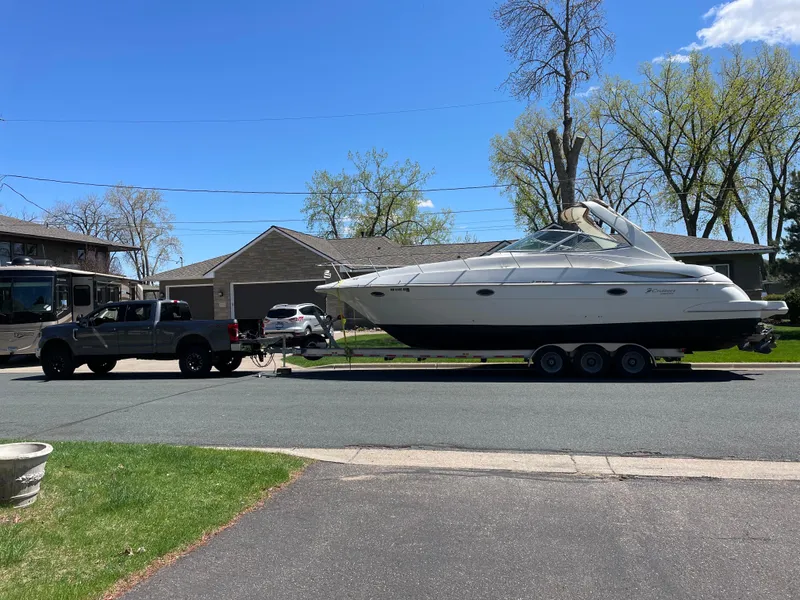 Slide: The Image of 2001 Cruisers Yachts 3470 Express on trailer, towed by a truck in a suburban neighborhood. - 6