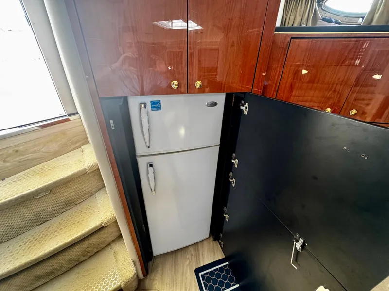 Slide: The Image of 2001 Sea Ray 460 Sundancer interior with wooden cabinets and a white refrigerator. - 19
