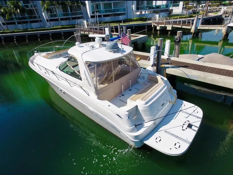 Slide: The Image of 2001 Sea Ray 460 Sundancer yacht docked in a marina, surrounded by clear green water. - 2